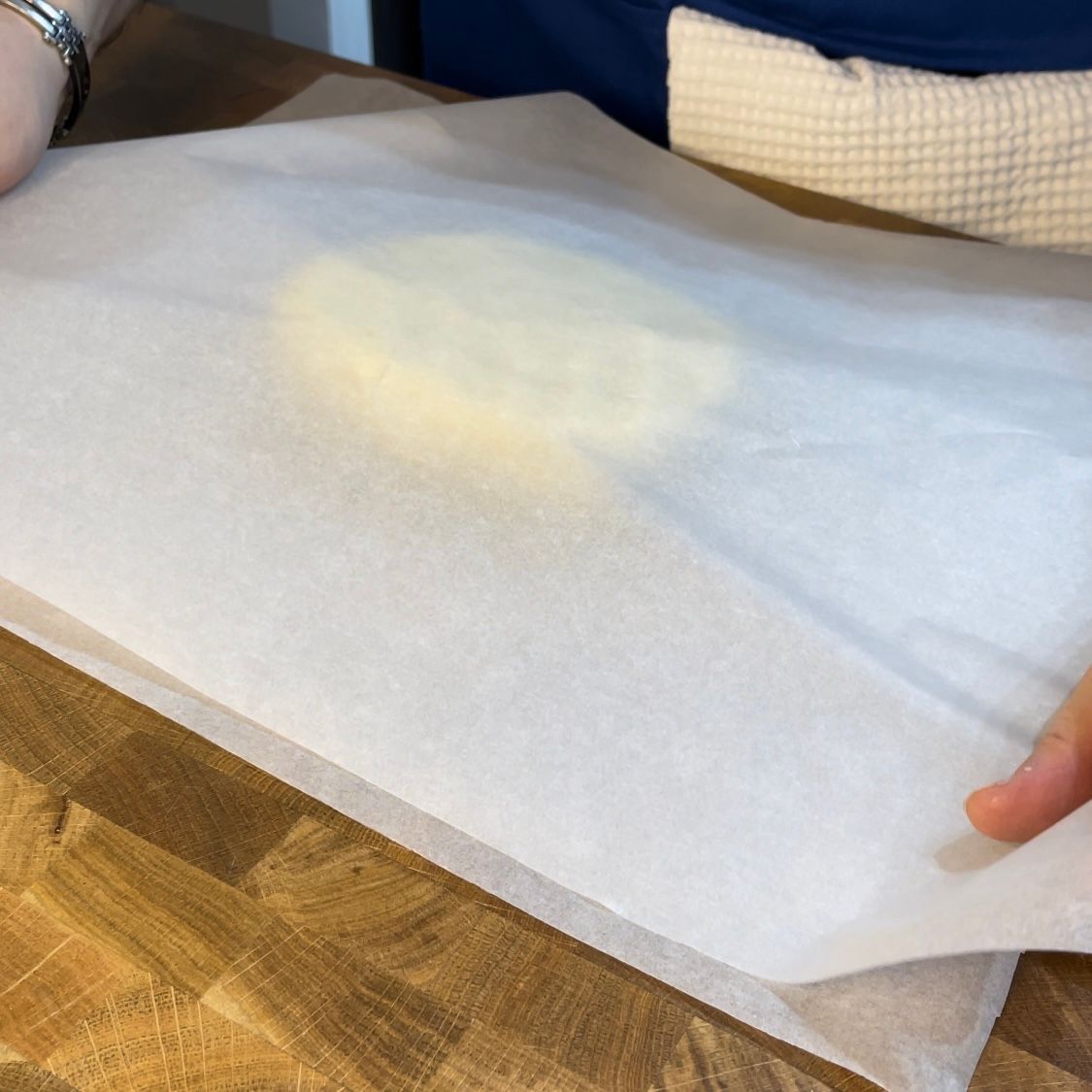 Una persona tiene in mano un pezzo di carta oleata su un tavolo di legno