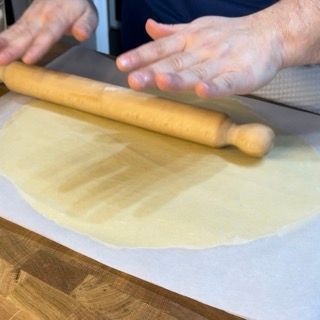 Sfoglia di pasta frolla su un vassoio, pronta per il riposo in frigo.