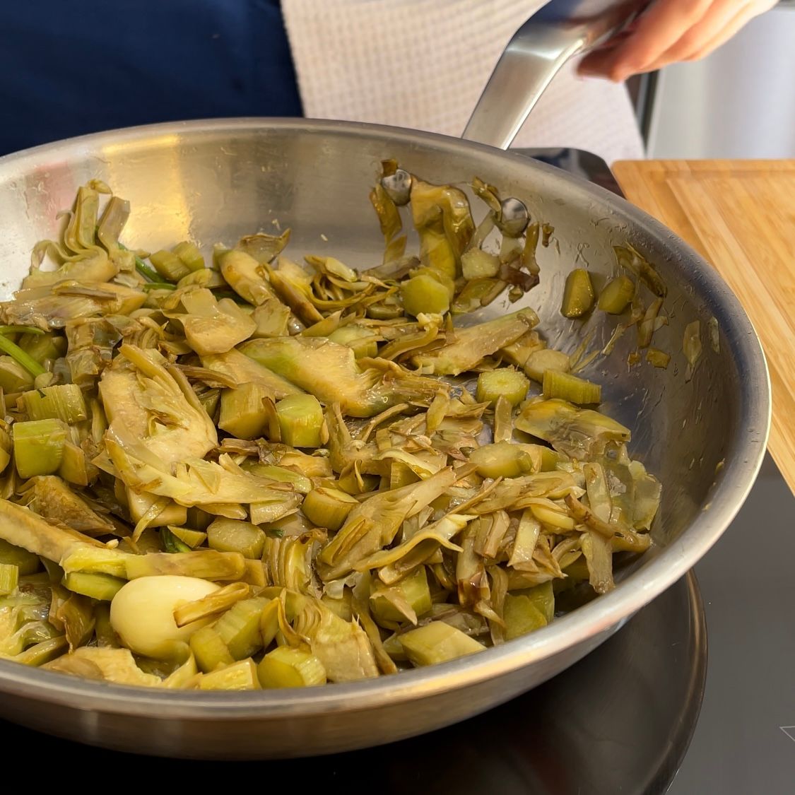 Una padella piena di verdure viene mescolata da una persona