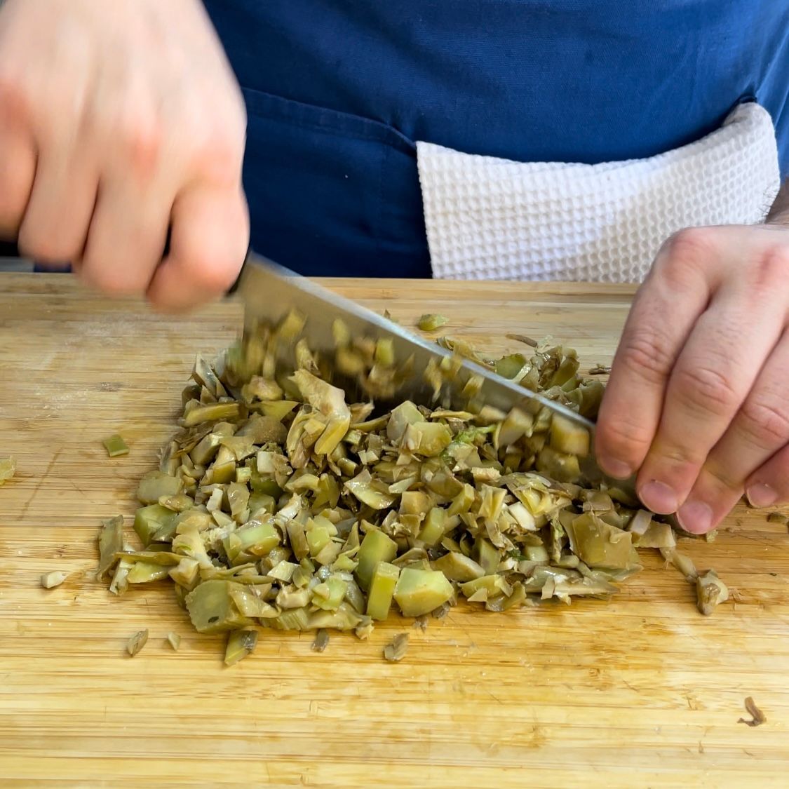 Una persona sta tagliando le verdure su un tagliere di legno