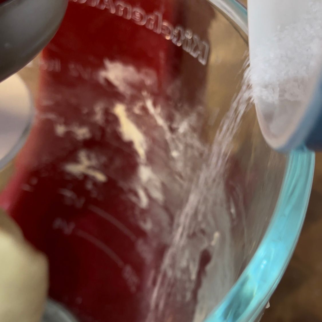 Una persona sta versando acqua in un misurino su cui è scritto KitchenAid