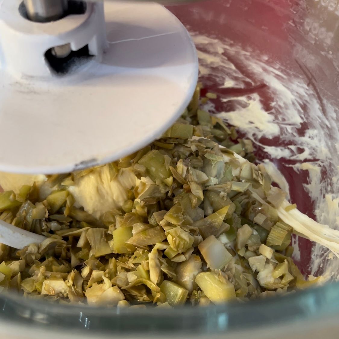 Primo piano di un robot da cucina pieno di verdure tritate.