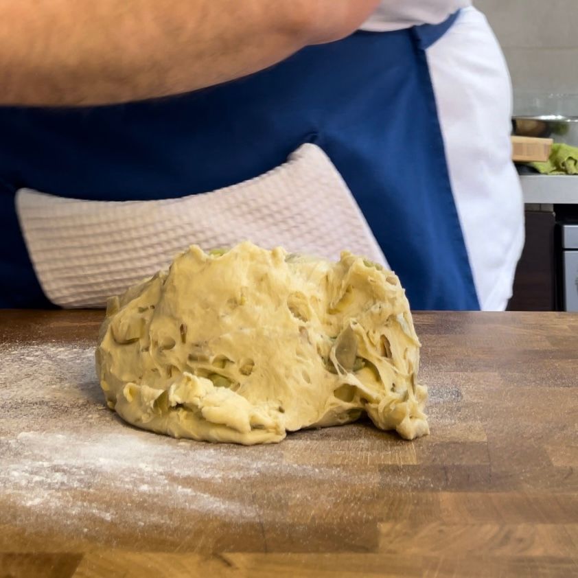 Una persona sta impastando la pasta su un tagliere di legno