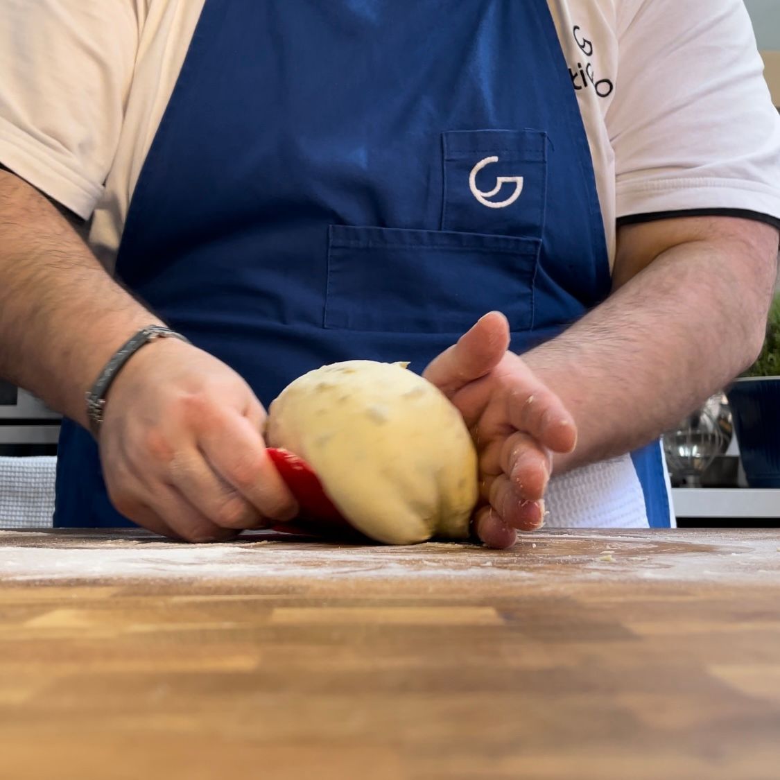 Un uomo che indossa un grembiule blu con la lettera g sopra