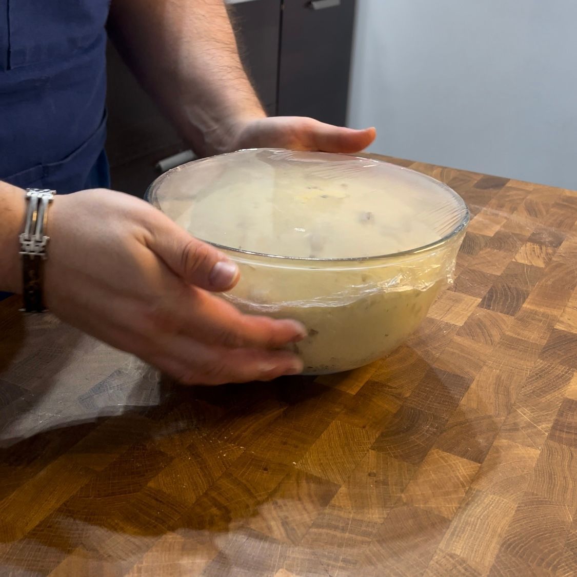 Una persona tiene in mano una ciotola di zuppa su un tavolo di legno