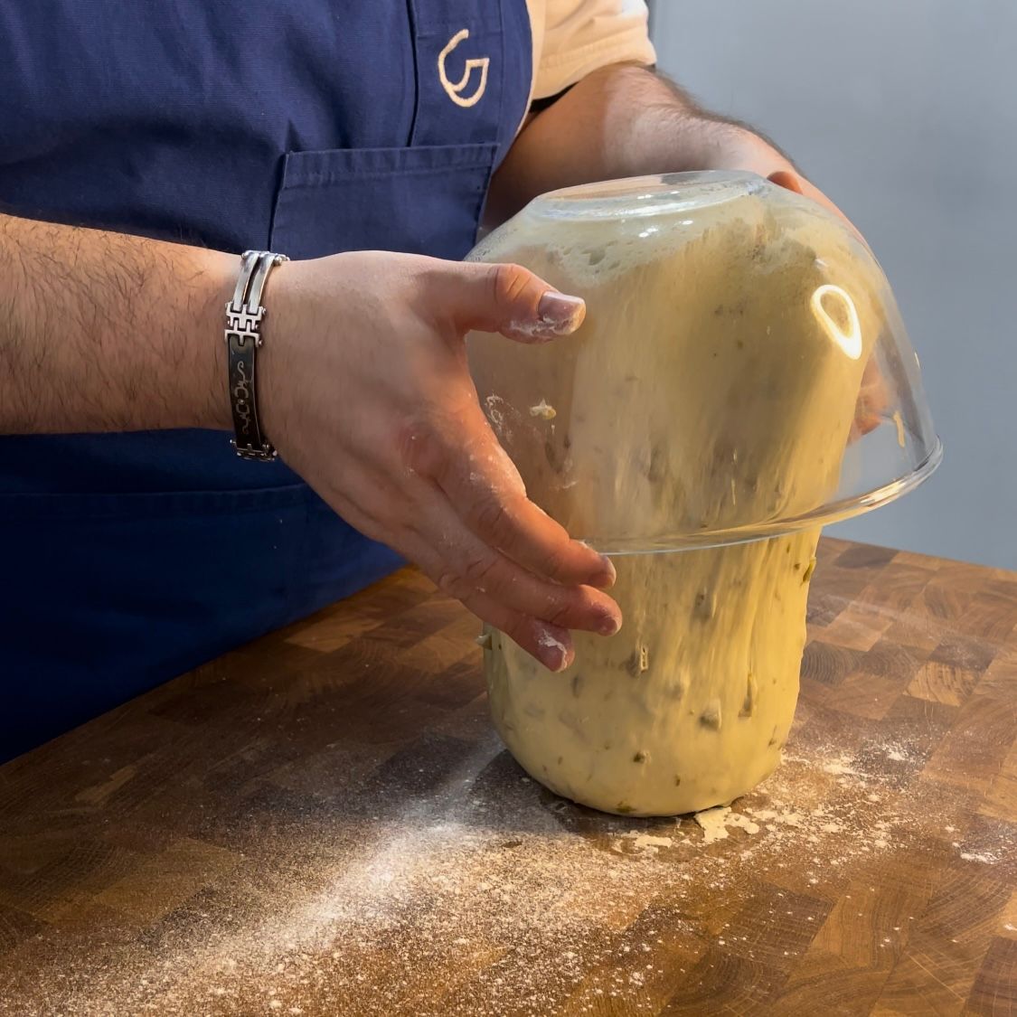 Una persona tiene in mano una ciotola di pasta su un tavolo di legno