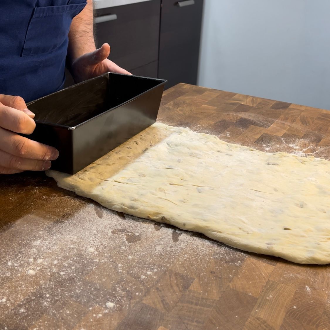 Una persona tiene una padella sopra un pezzo di pasta