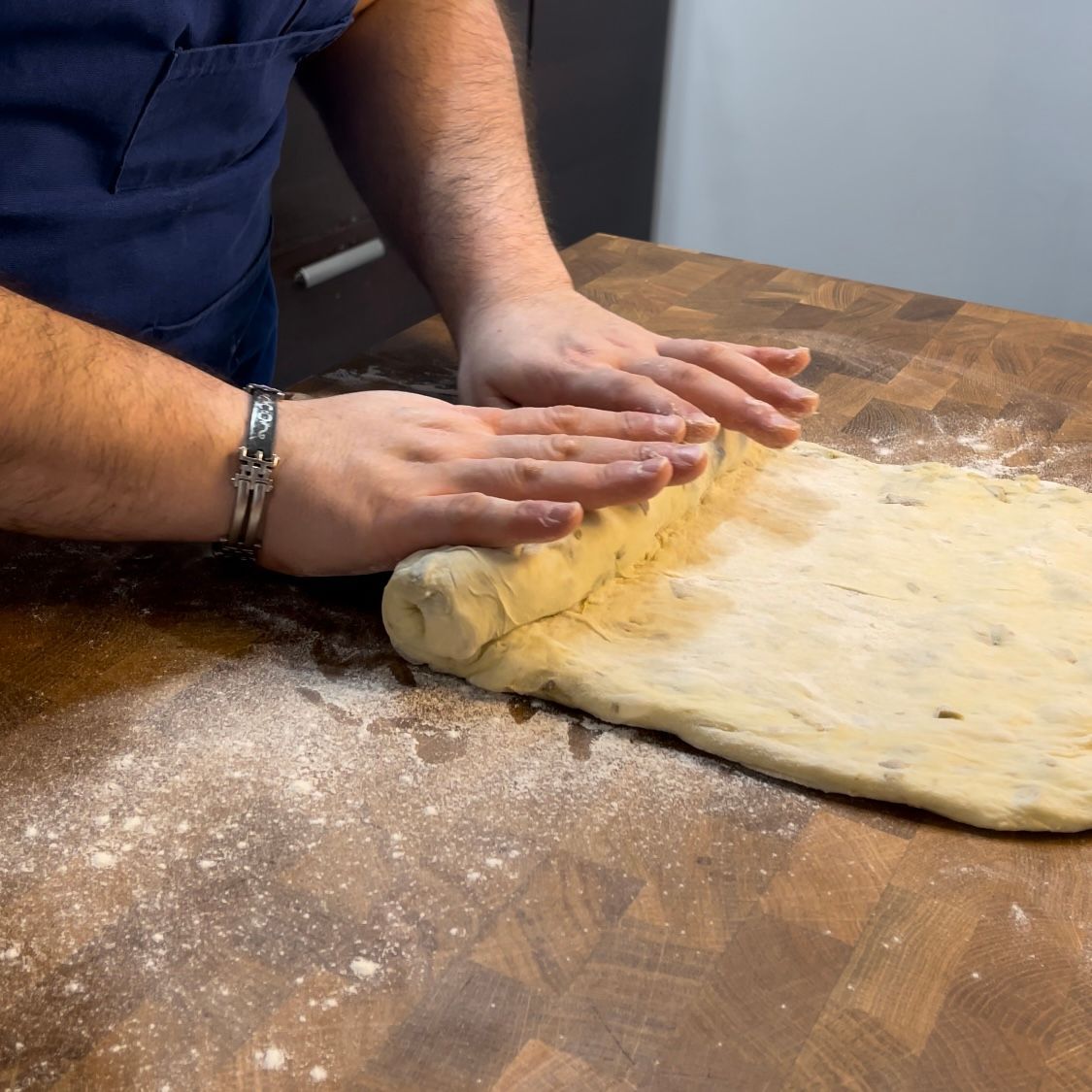 Una persona sta stendendo la pasta su un tavolo di legno