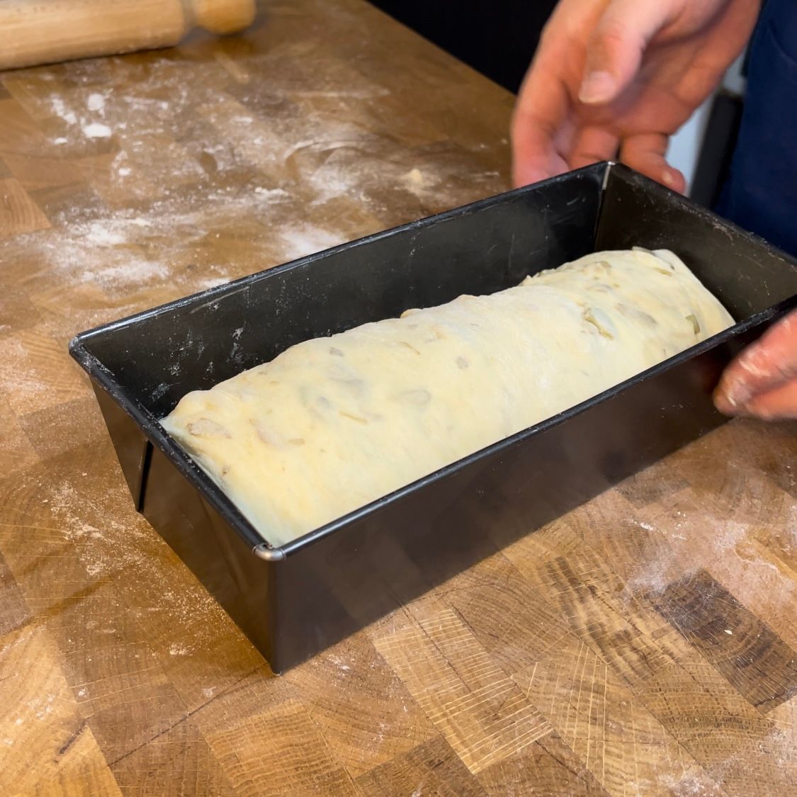 Una pagnotta di pane è in una padella su un tavolo di legno
