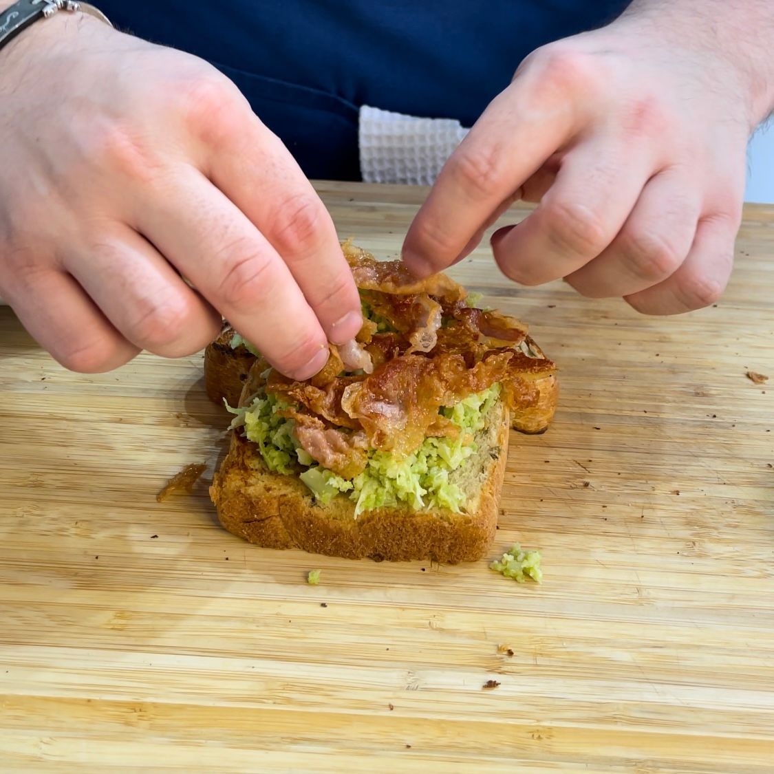Una persona sta preparando un panino su un tagliere di legno