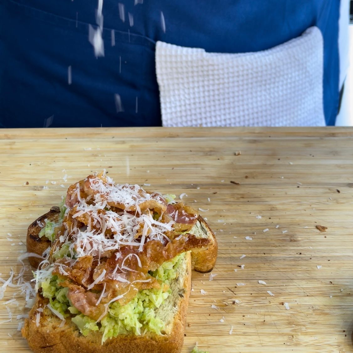 Una persona sta cospargendo di sale un panino su un tagliere di legno.