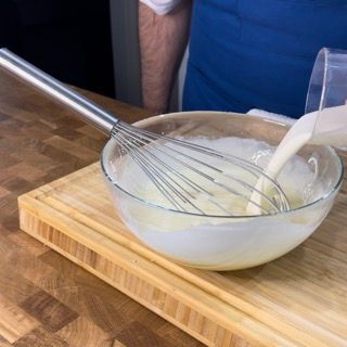 Una persona sta versando il latte in una ciotola con una frusta