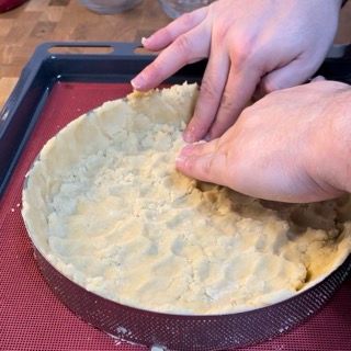 Una persona sta preparando una crosta di torta con le mani