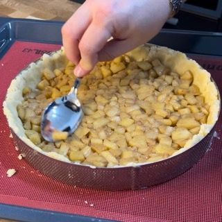 Una persona tiene un cucchiaio sopra una torta di mele