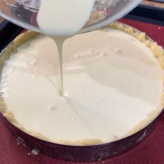 Una persona sta versando un liquido bianco nella pasta di una torta.