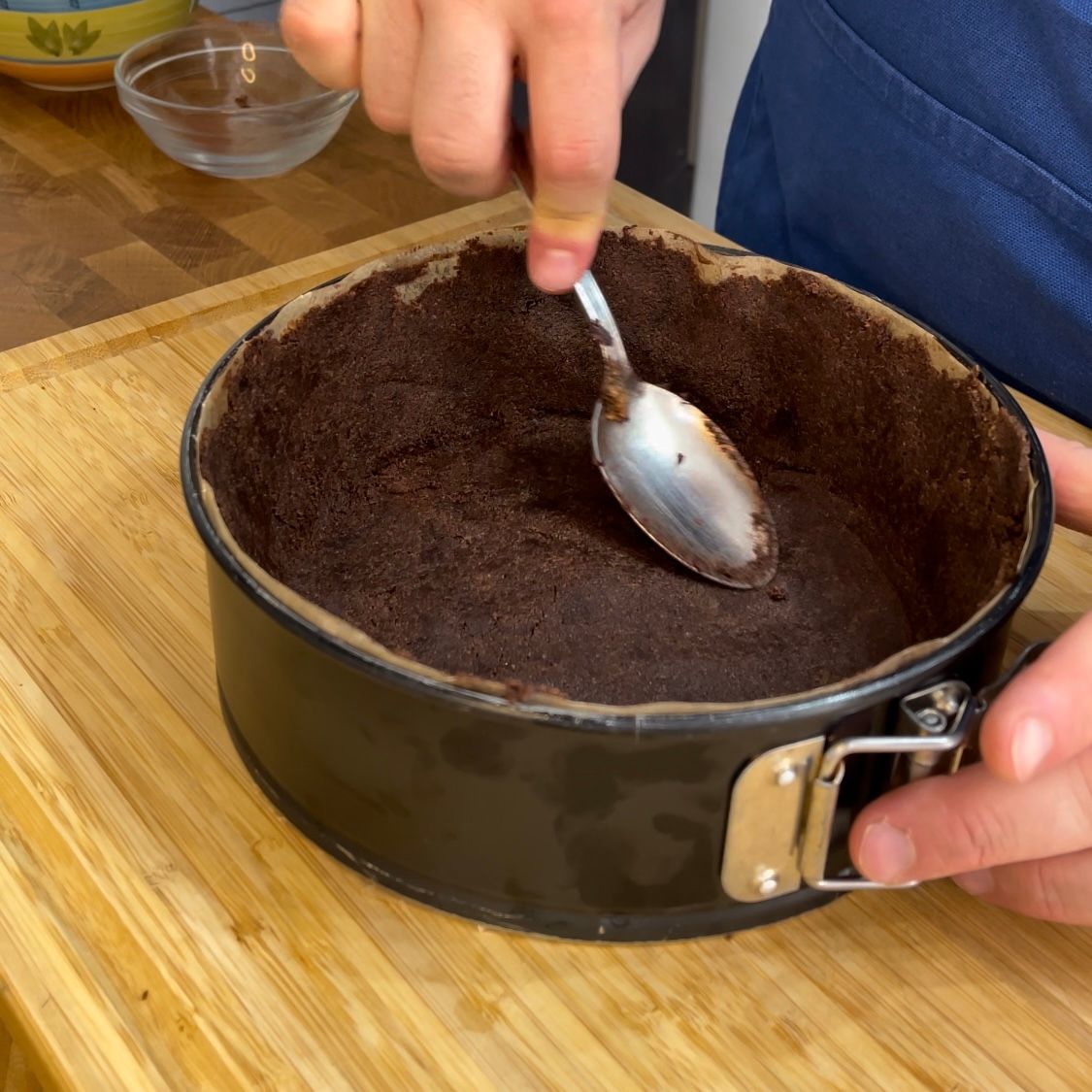 Una persona tiene in mano un cucchiaio in una tortiera