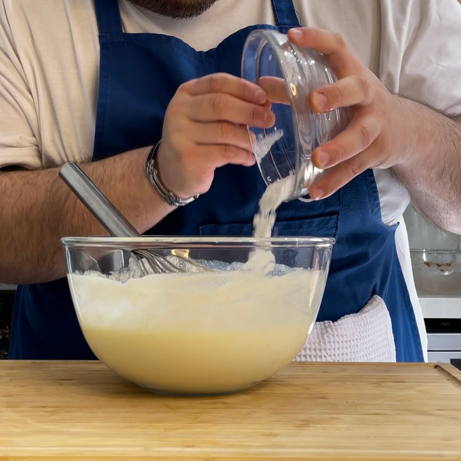 Un uomo che versa qualcosa in una ciotola con una frusta