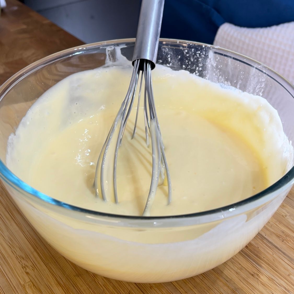 Una ciotola di vetro piena di un liquido giallo con una frusta dentro