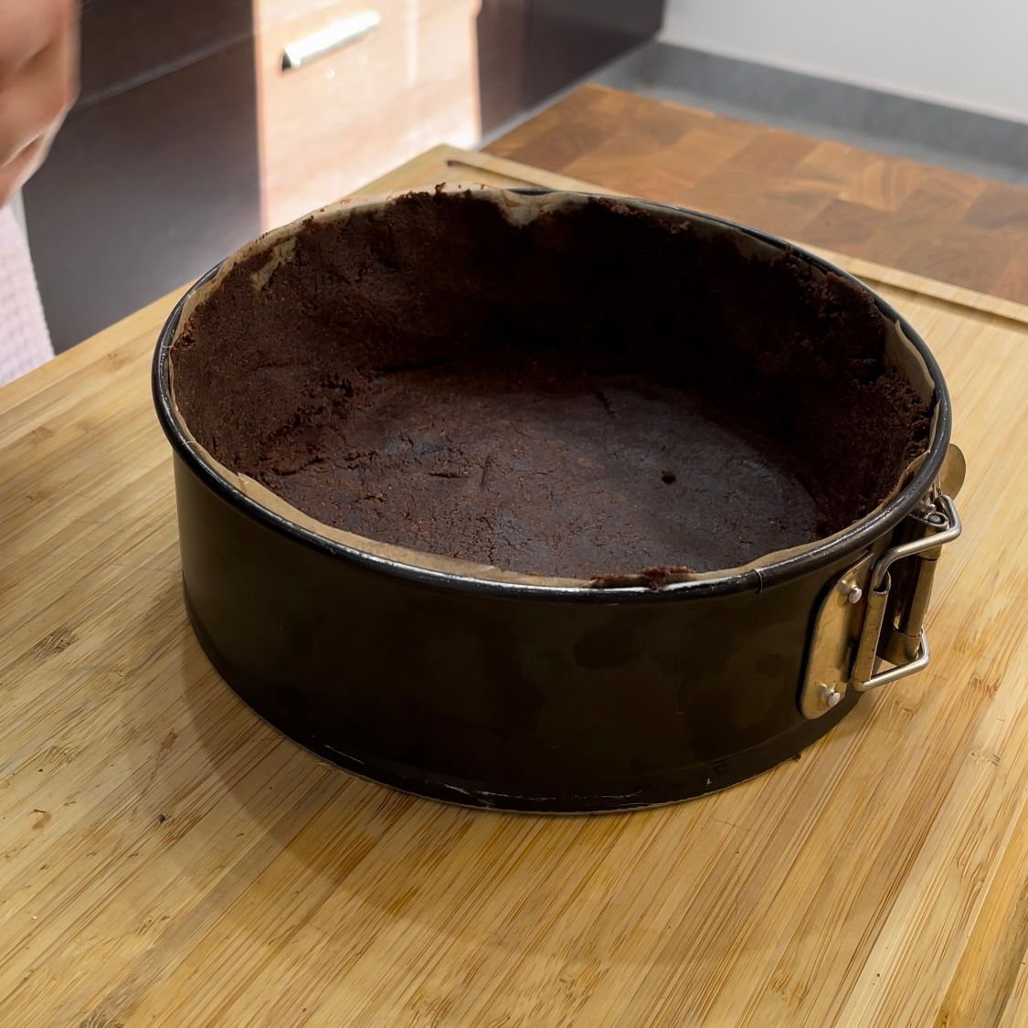 Una tortiera è appoggiata su un tagliere di legno