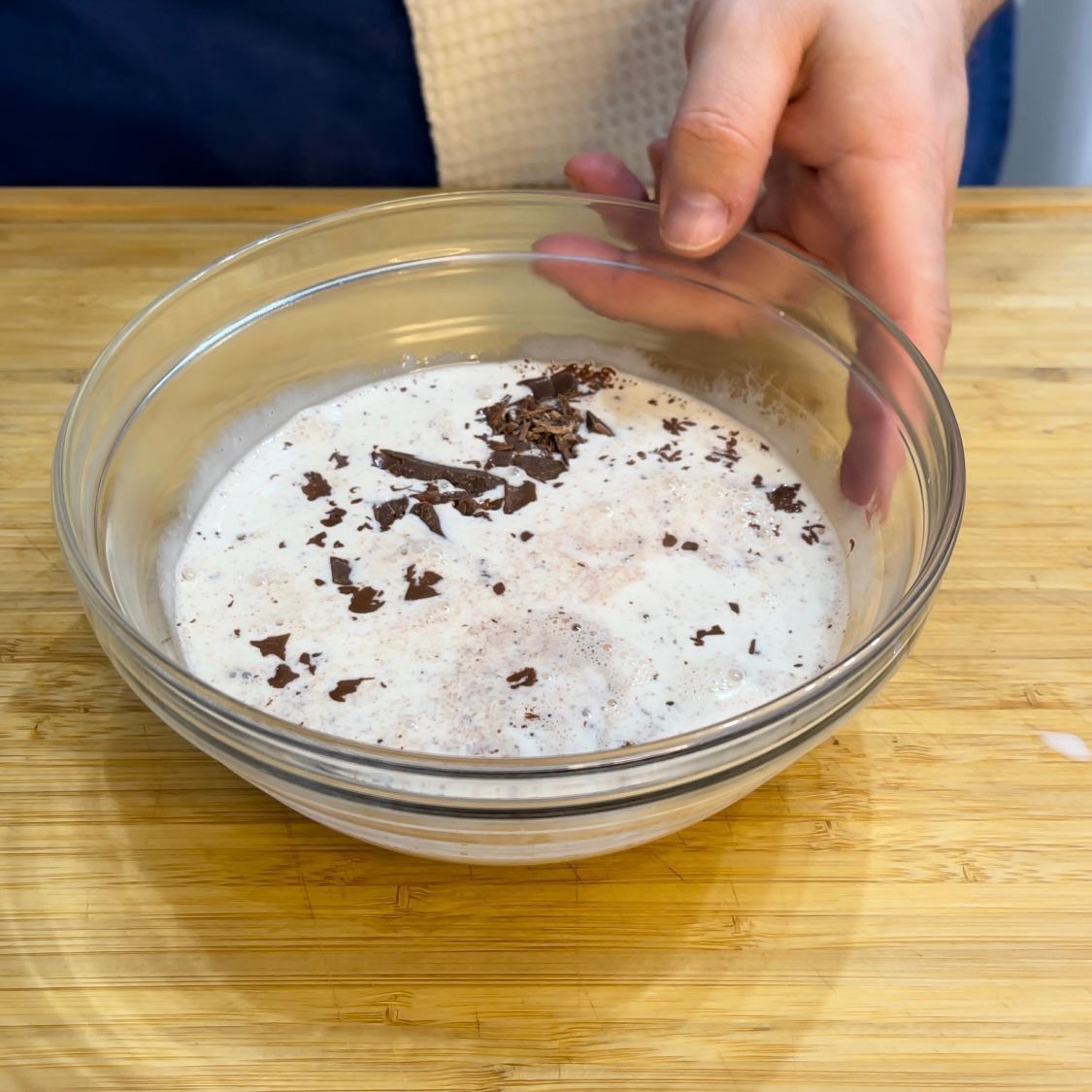 Una persona sta mescolando una ciotola di cibo con scaglie di cioccolato sopra.