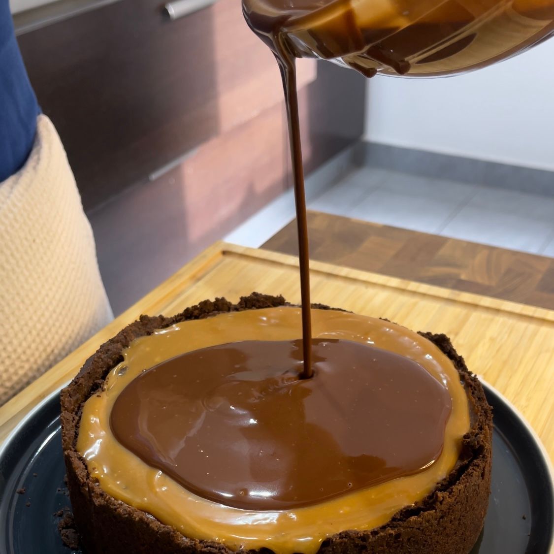 Una persona sta versando la salsa al cioccolato su una torta al cioccolato