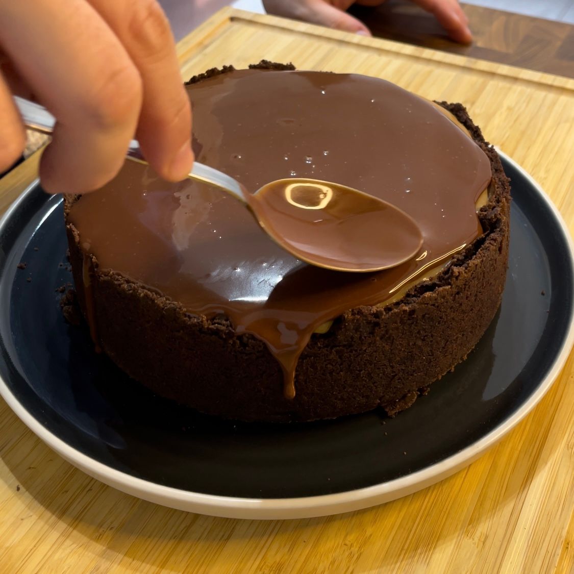 Una persona sta immergendo un cucchiaio in una torta al cioccolato