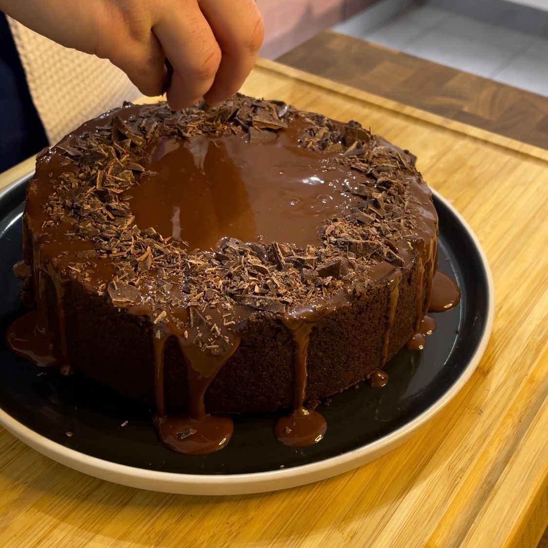 Una persona sta tagliando una torta al cioccolato su un piatto