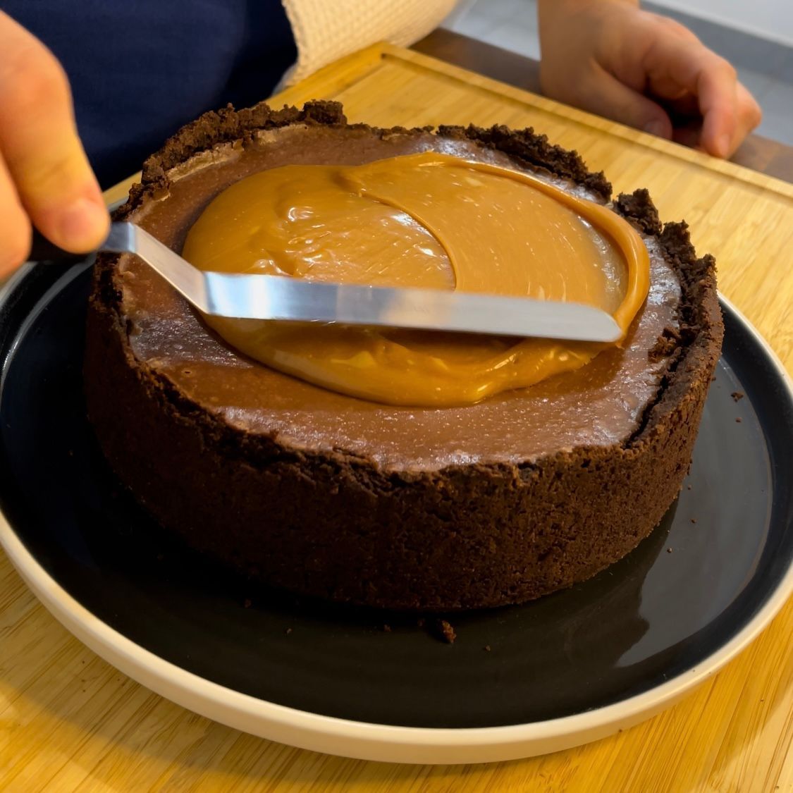 Una persona sta tagliando una torta al cioccolato con una spatola