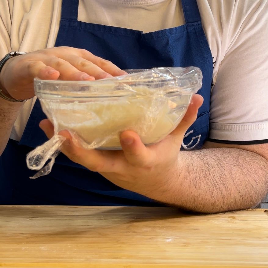 Una persona con un grembiule tiene in mano una ciotola di cibo