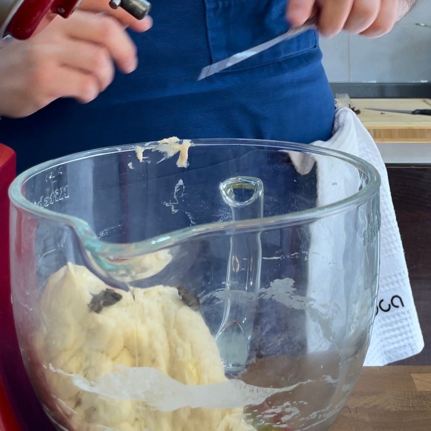 Una persona sta tagliando un pezzo di pasta in una ciotola di vetro