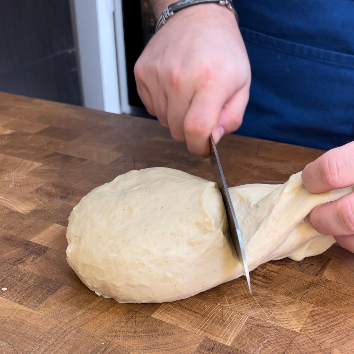 Una persona sta tagliando un pezzo di pasta su un tagliere