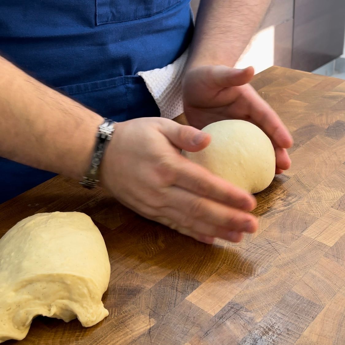 Una persona tiene in mano una palla di pasta su un tagliere