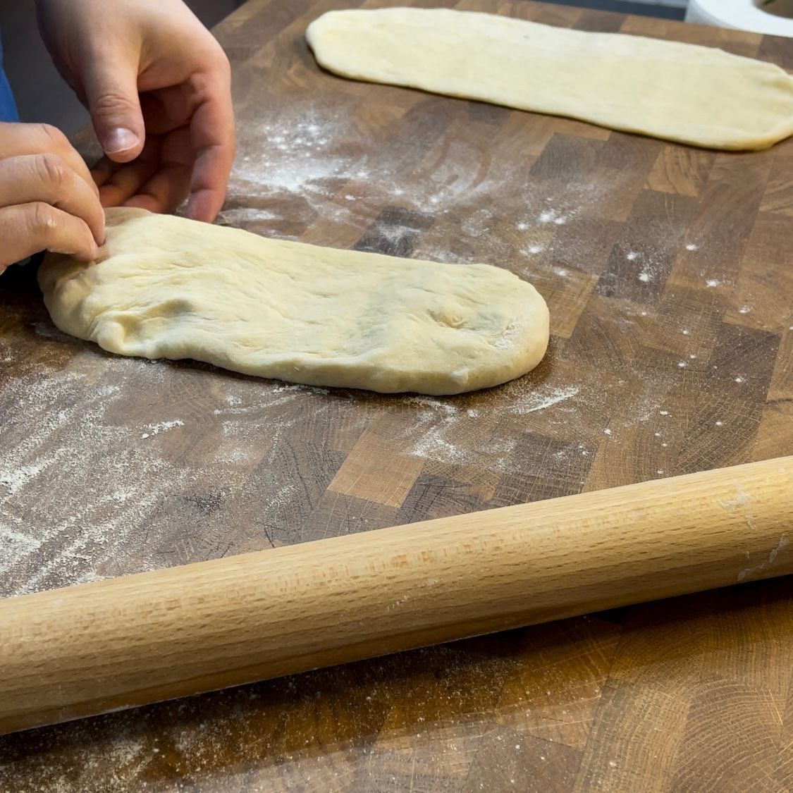 Una persona sta stendendo la pasta con un mattarello