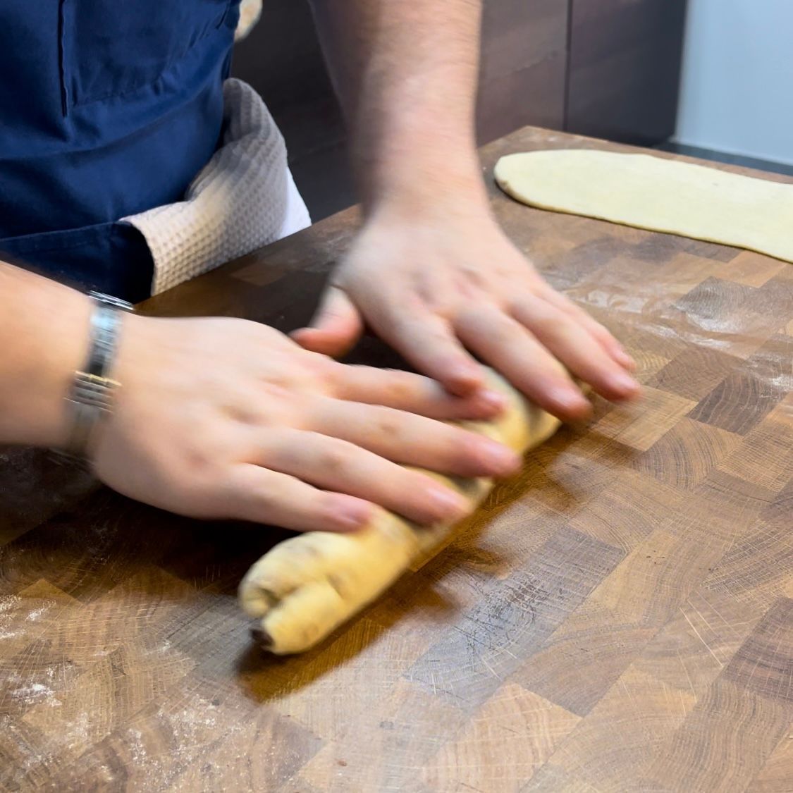 Una persona sta impastando l'impasto su un tagliere di legno.