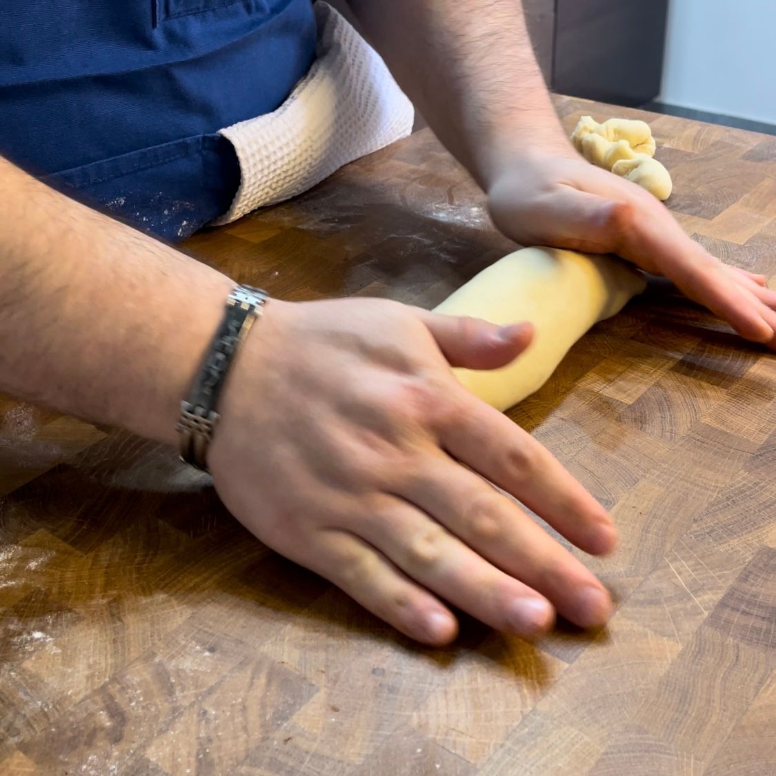 Una persona che indossa un orologio sta stendendo la pasta su un tagliere