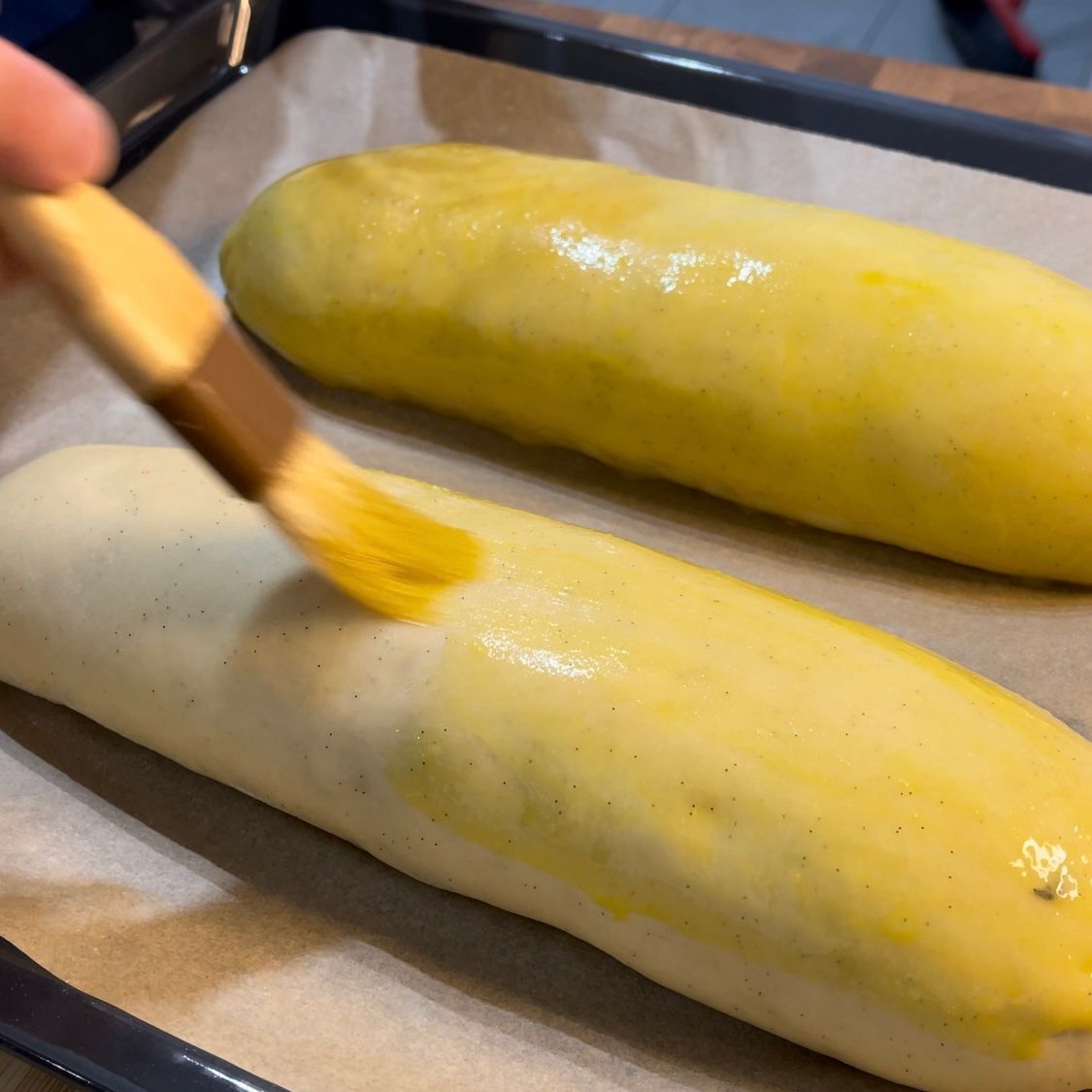Una persona sta applicando la salsa gialla su una pagnotta di pane