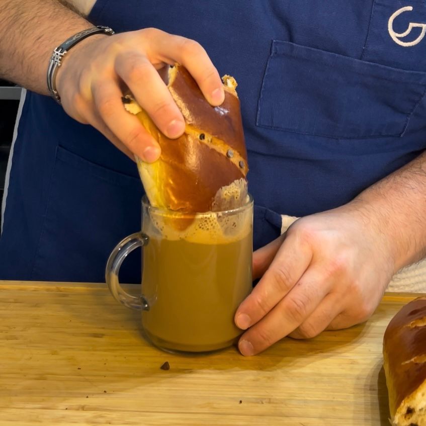 Una persona sta versando un pretzel in una tazza di caffè