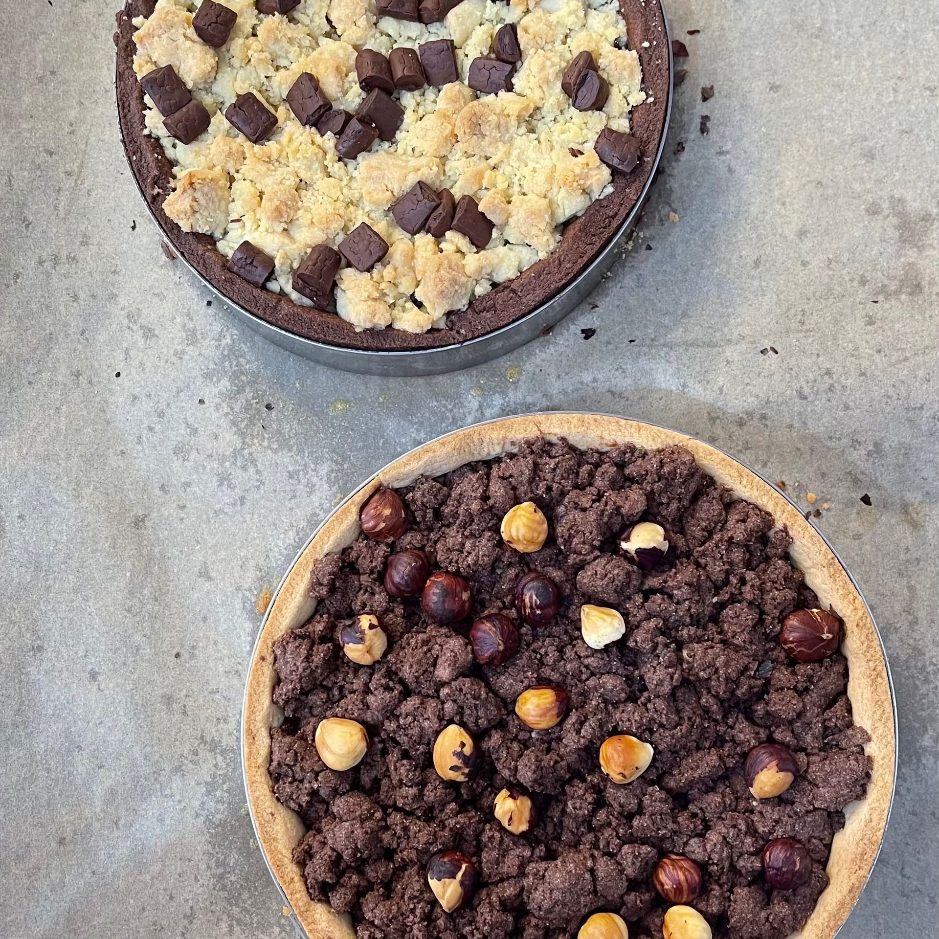 Due torte con cioccolato e nocciole sono appoggiate su un tavolo.