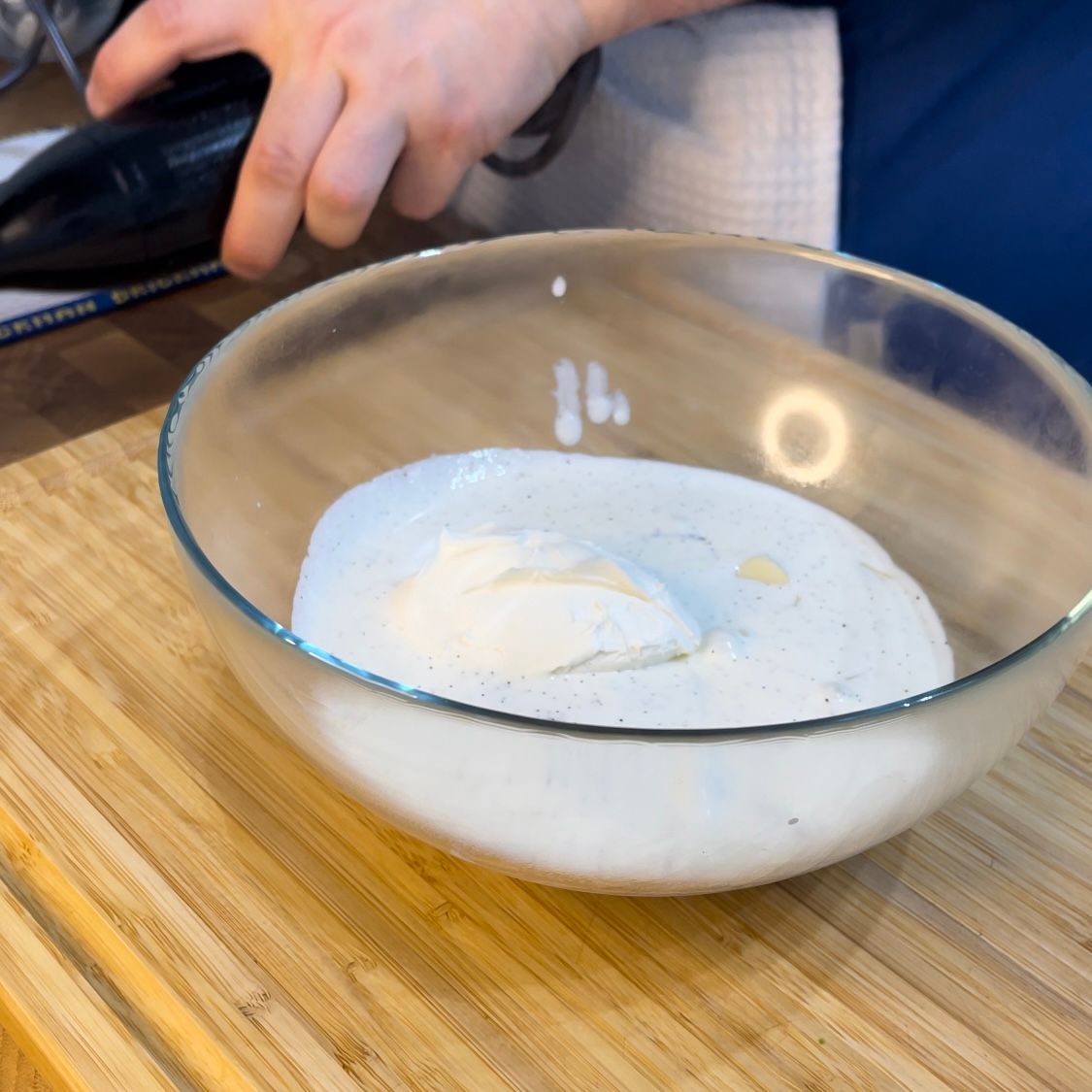 Una ciotola di liquido bianco è su un tagliere di legno