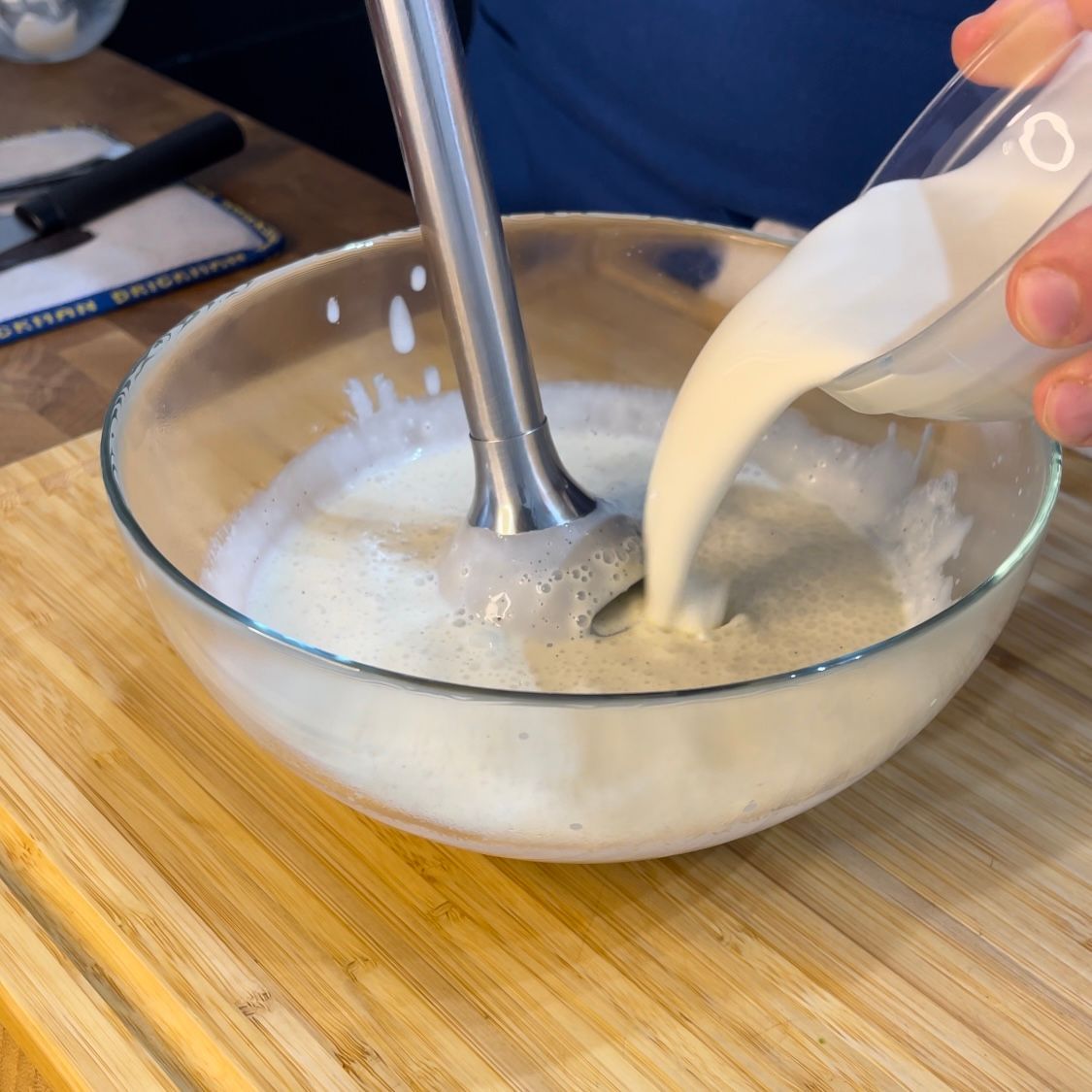 Una persona sta versando il latte in una ciotola di vetro