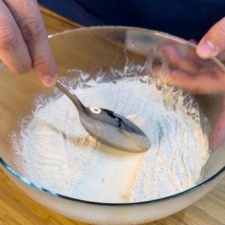 Una persona sta mescolando qualcosa in una ciotola con un cucchiaio