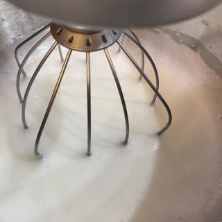 Un primo piano di una frusta in una ciotola di panna montata