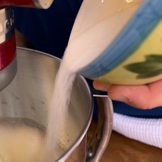 Una persona che versa lo zucchero in una ciotola da un mixer