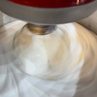 Primo piano di un mixer in una ciotola di panna montata.