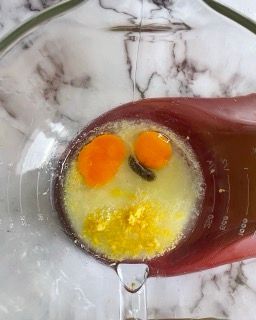 Primo piano di due uova in un misurino con un cucchiaio.