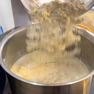 Una persona sta versando la farina in una ciotola piena di liquido.