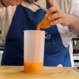 Una persona che versa del succo d'arancia in una tazza con la lettera g sopra