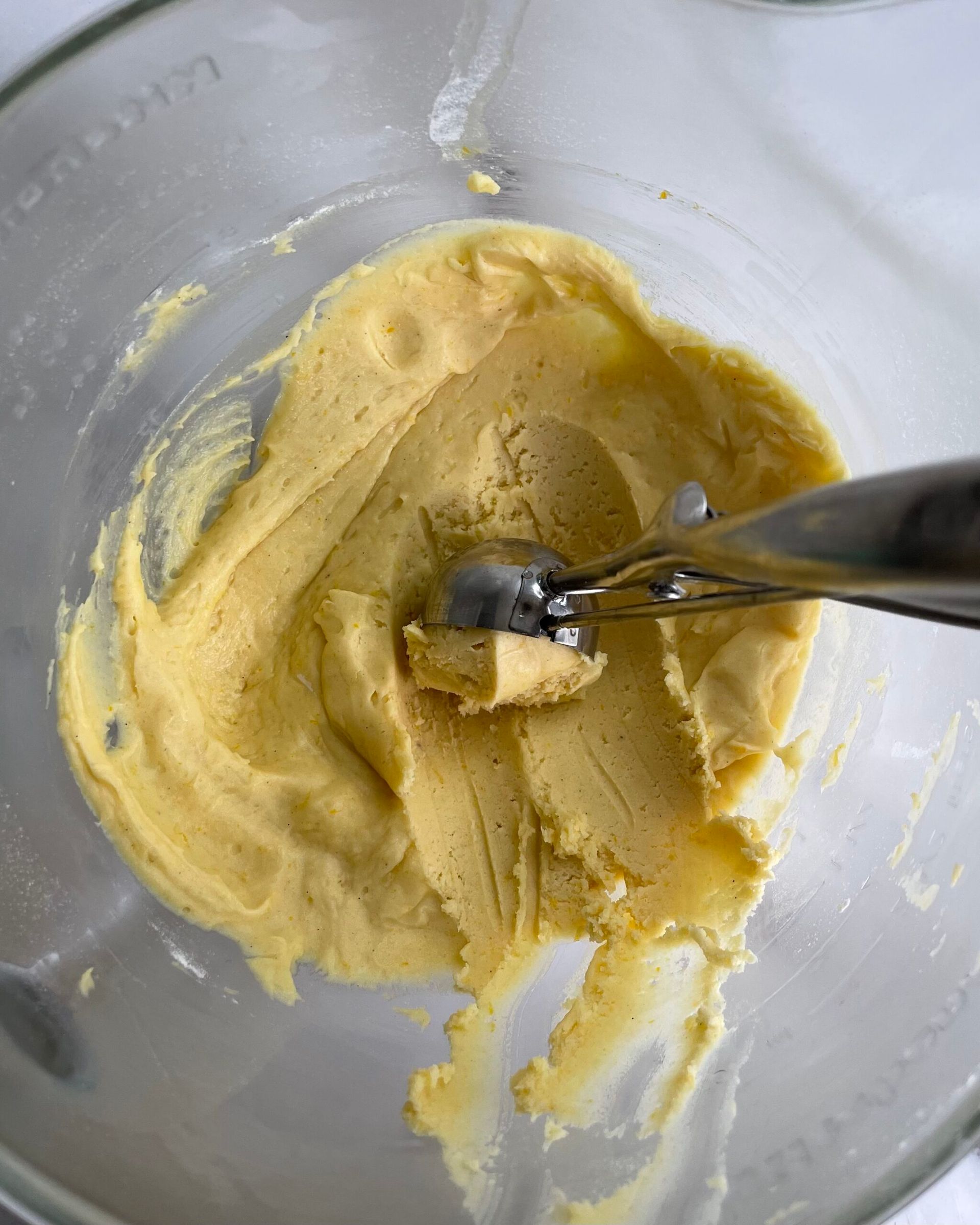 Primo piano di una ciotola di pastella con dentro un cucchiaio per gelato.
