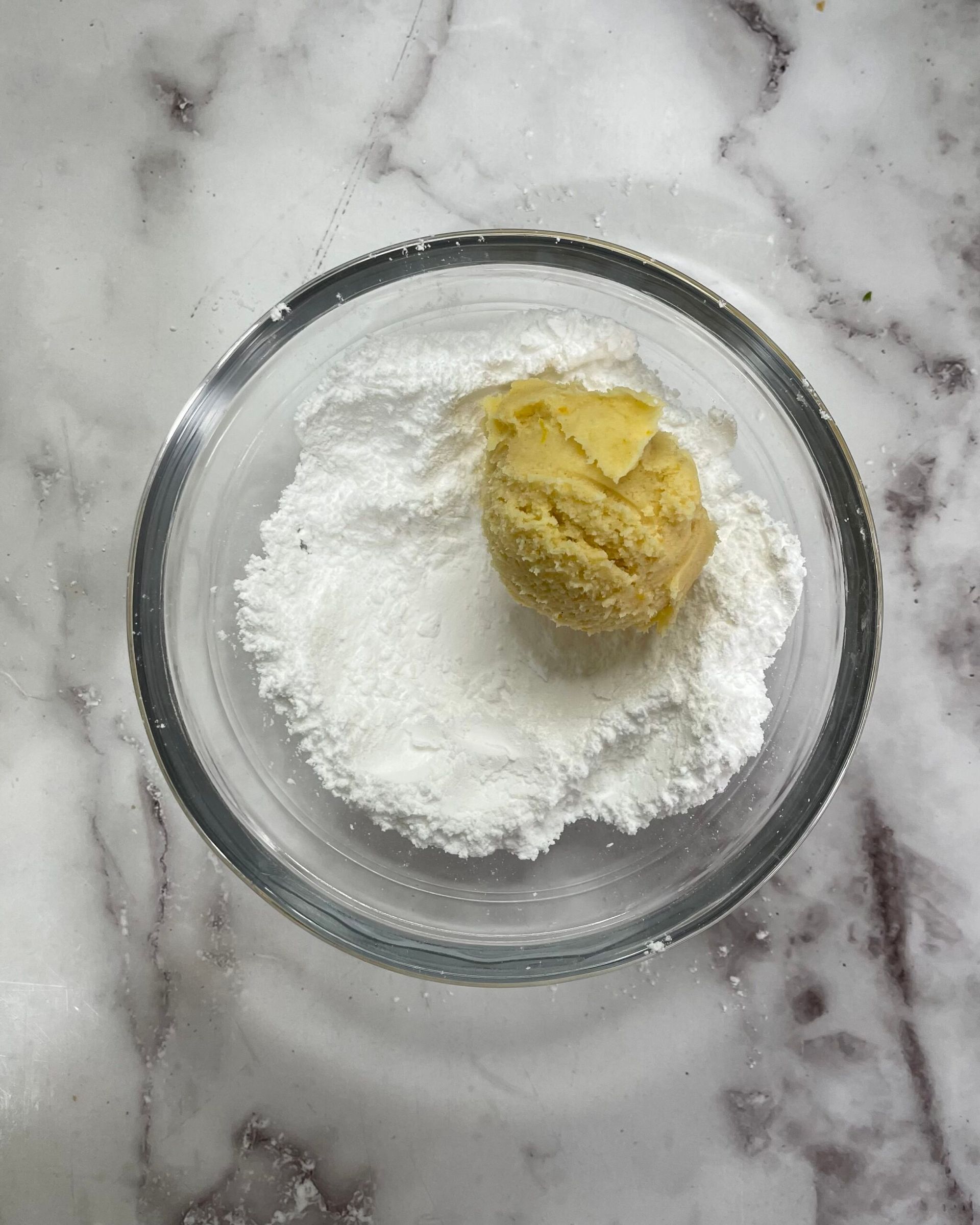 Una ciotola di vetro piena di zucchero a velo e un biscotto dentro.