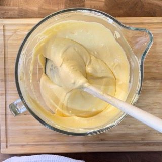 Una brocca di liquido giallo con un cucchiaio di legno dentro